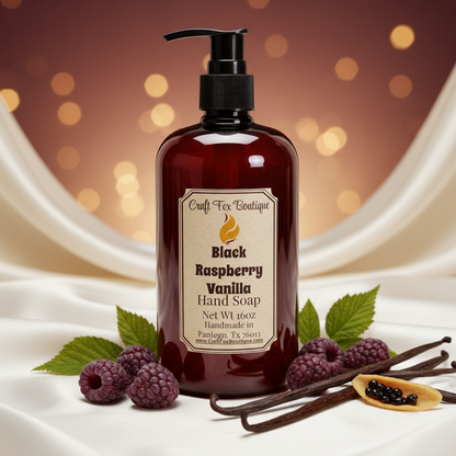 Bottle of Black Raspberry Vanilla Hand Soap with raspberries and vanilla beans on a draped fabric background